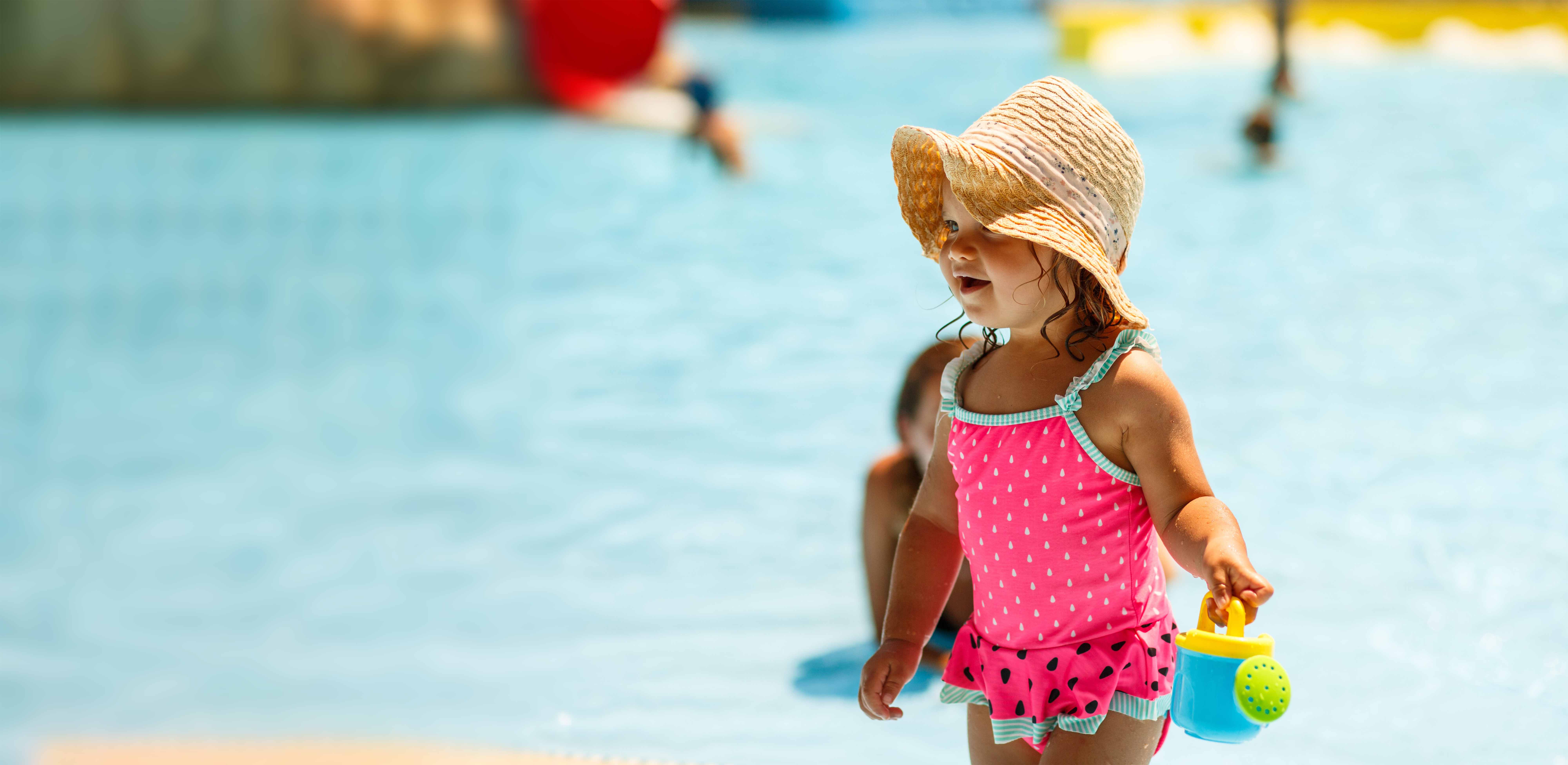 Toddler child wearing swimming suit and playing in clean swimming pool